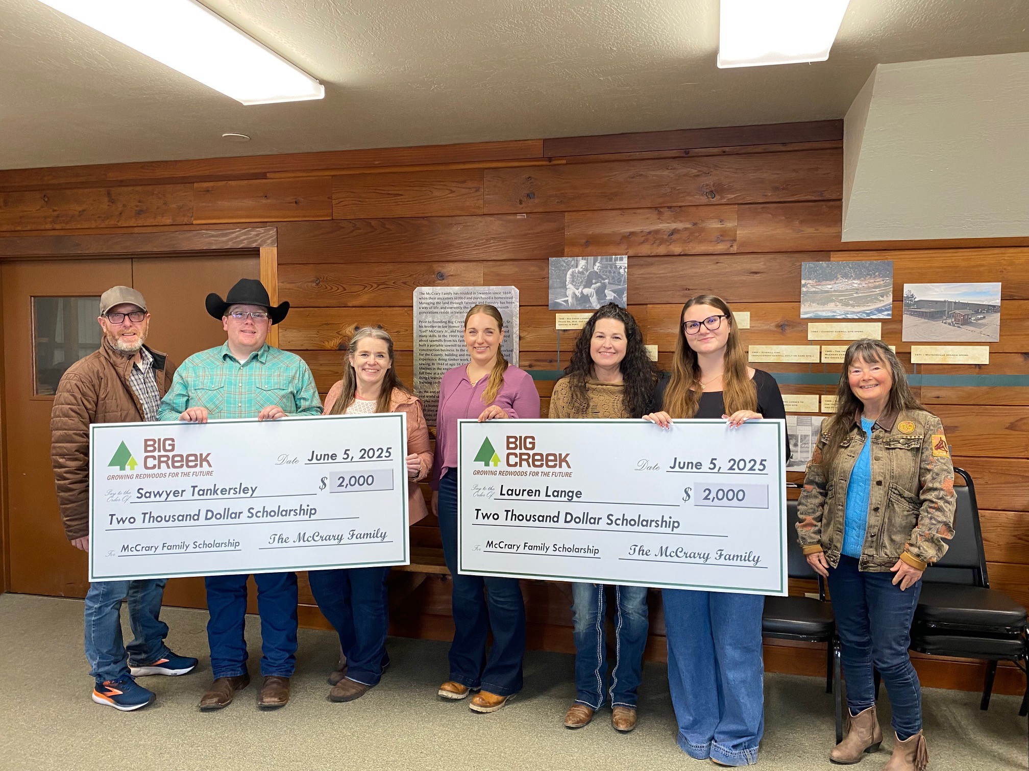 Scholarship recipients with their families and a Big Creek lumber representative holding big checks.