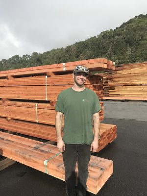 Man standing in front of stacks of wood