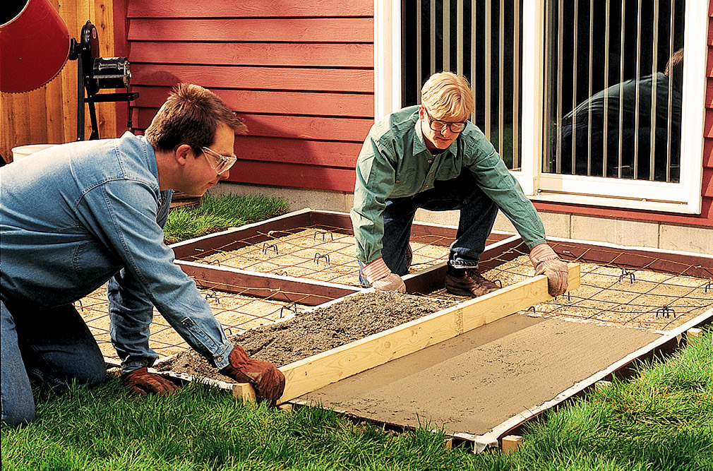 Two men floating concrete for an outdoor patio.