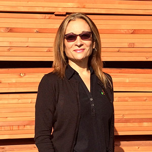 Esther Rocha in front of a stack of wood.