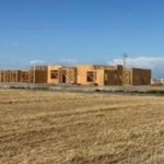 Building being framed with a field in the foreground