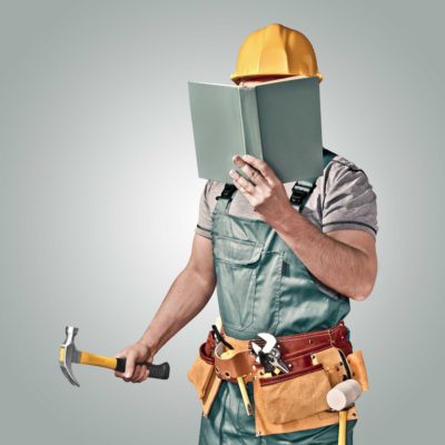 Contractor with hammer reading a book
