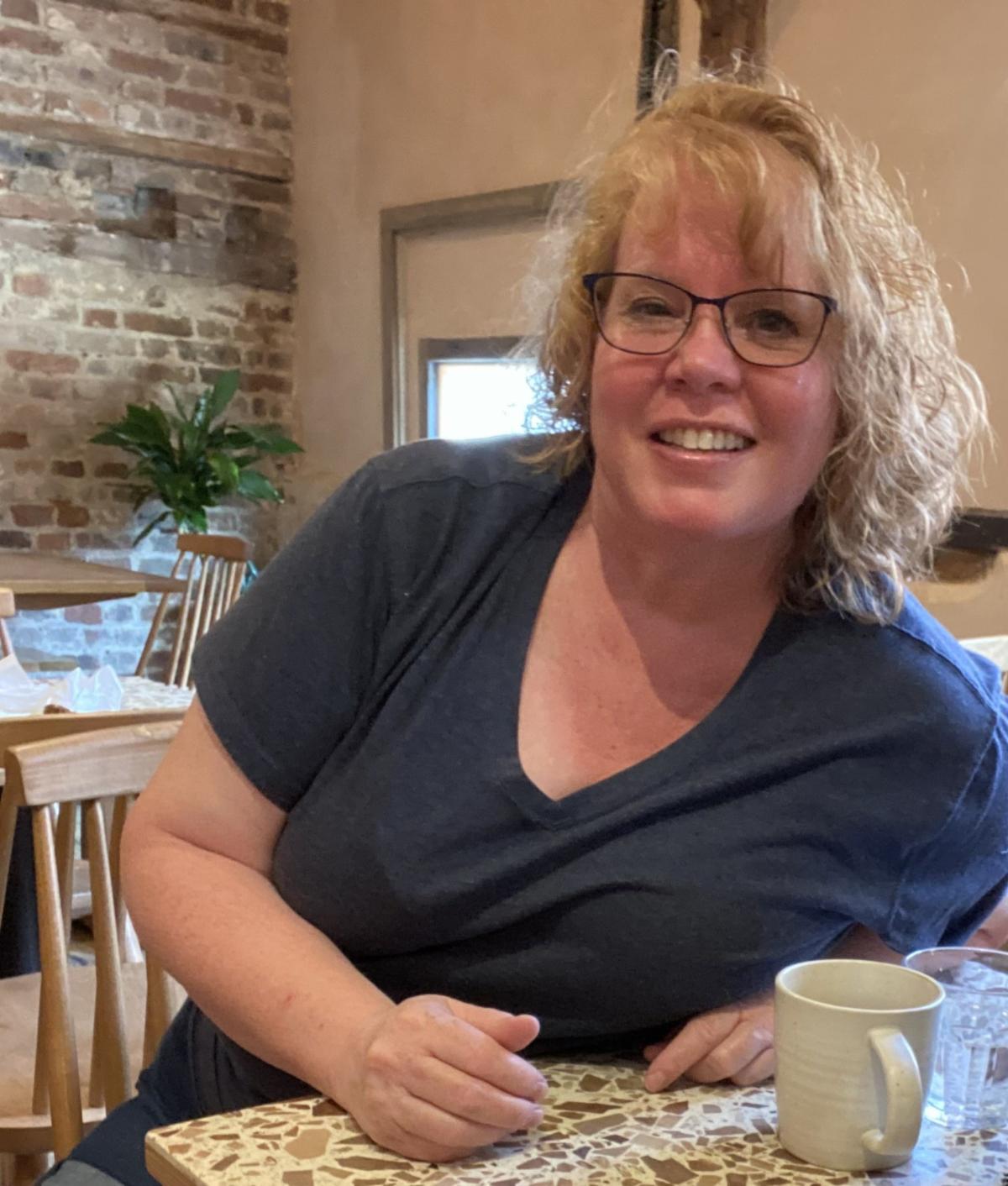 WOMAN SMILING AT A TABLE WITH A COFFEE CUP