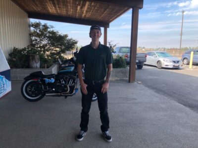 Man standing with his hands in his pockets in front of a motorcycle