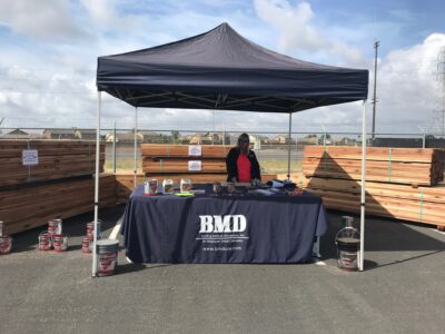 Woman standing at booth in front of a stack of wood