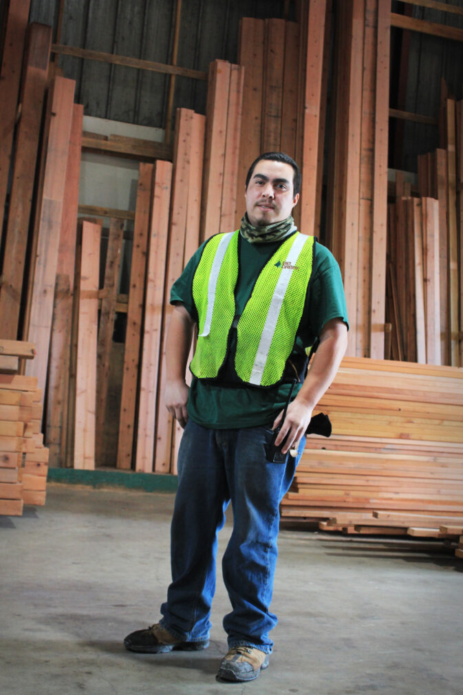 Man in Safety Vest Standing in front of Lumber