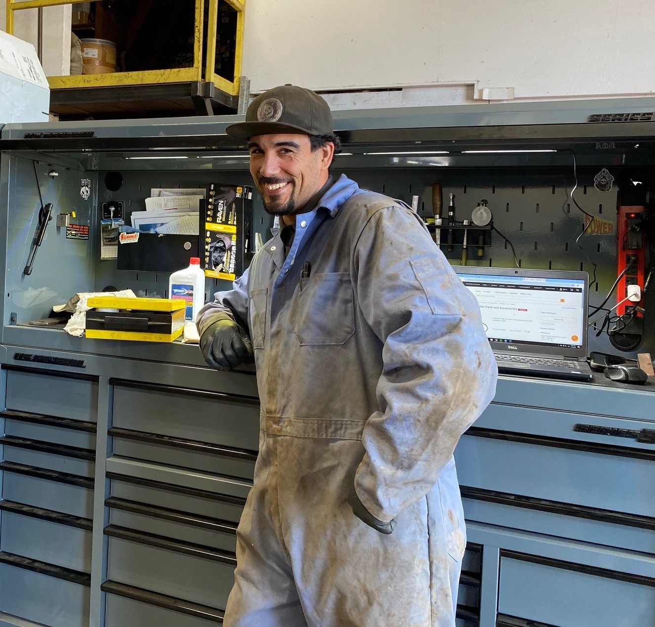 Man in coveralls leaning against a toolbox