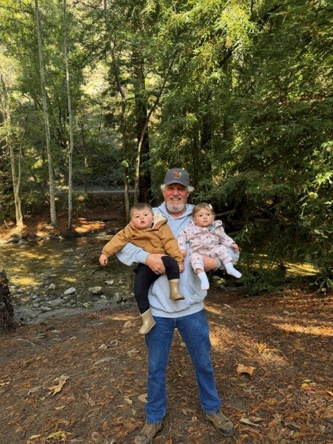 Man in forest holding a baby and a toddler