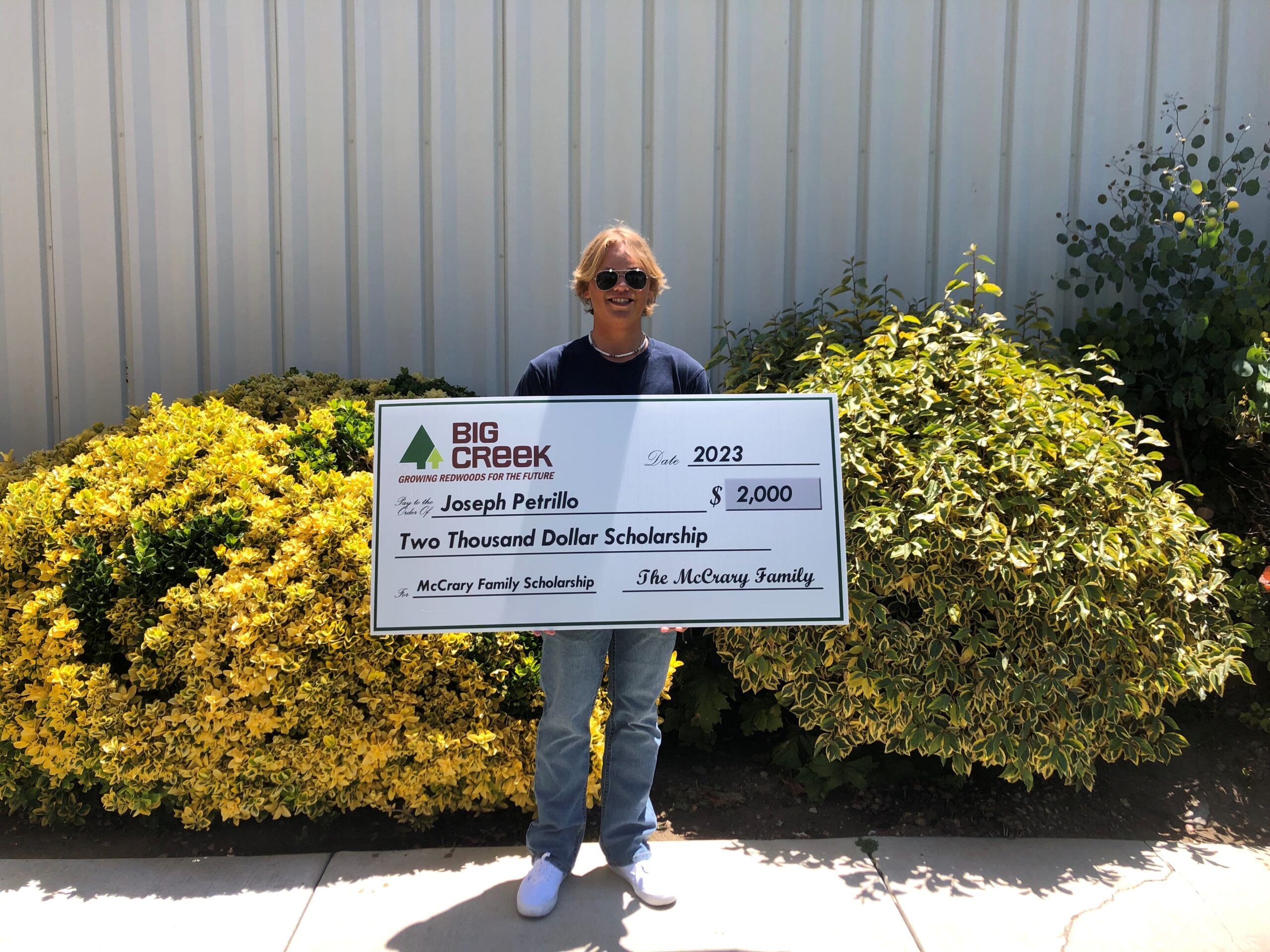 Student holding a big check getting a scholarship.