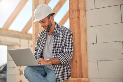 Contractor with a hard hat on leaning against a wall at a construction site